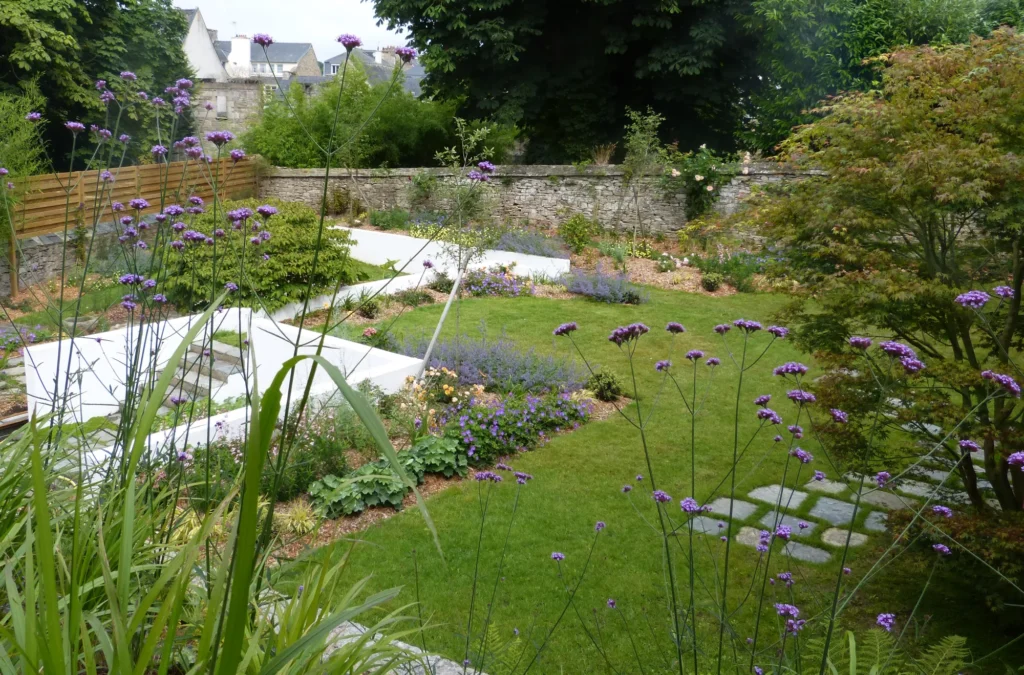 Jardin paysager aménagé avec des massifs fleuris, des allées en pierre et une pelouse bien entretenue à Lannion, Trégor, Côtes-d’Armor.