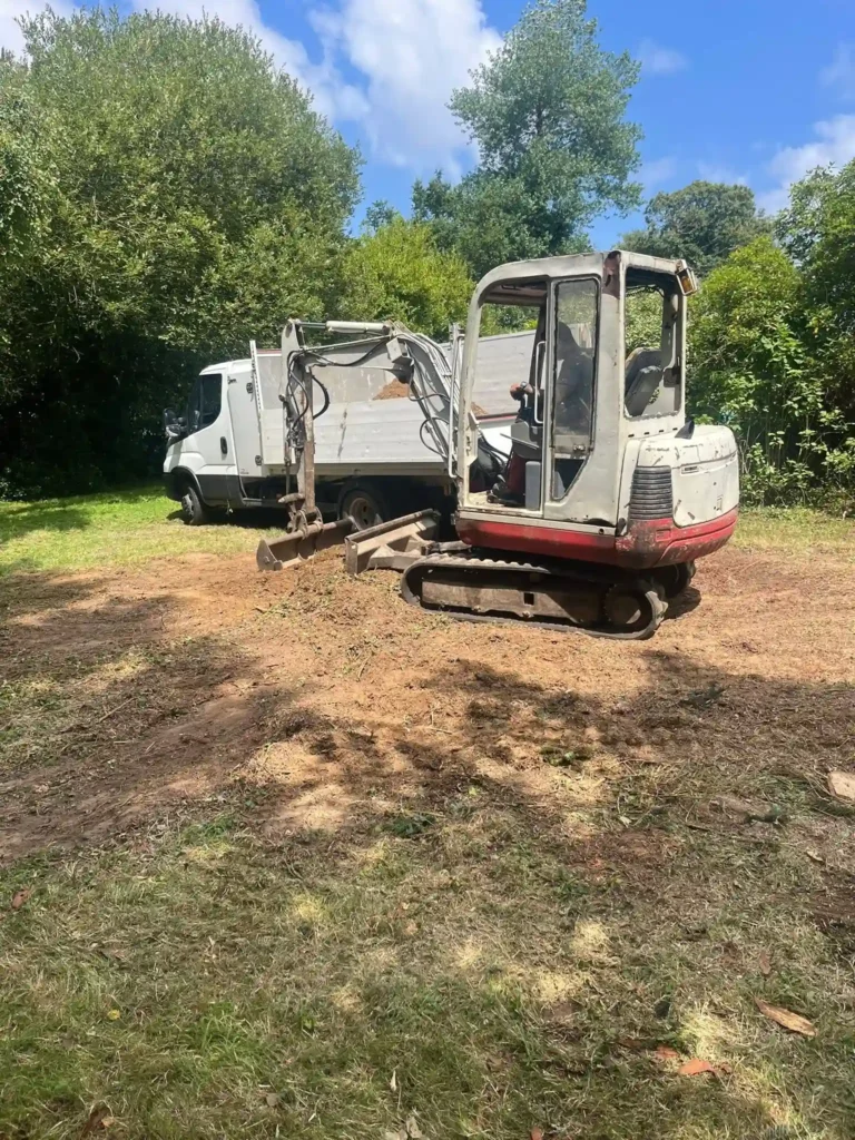 Mini-pelle nivelant le sol après abattage – Établissement Rochelle, paysagiste Lannion, entretien de jardin.